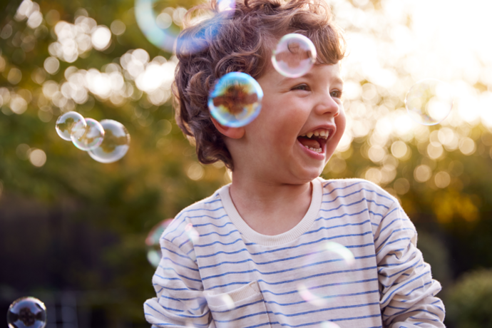 Porträt kleiner Junge lacht mit Seifenblasen